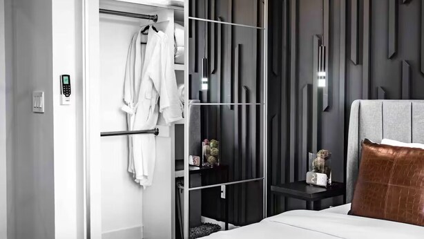 Een moderne slaapkamer met een bed, nachtkastje, kledingkast en spiegel.