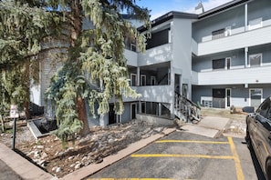 A multi-story building with a parking area, a covered outdoor seating area, and a staircase leading to the upper floors. - Relaxed 1BR Mountain Escape | Fireplace & Parking (Steamboat Springs)
