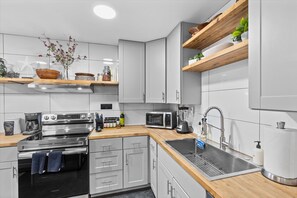 A modern kitchen with stainless steel appliances, wooden countertops, and white cabinetry. - Relaxed 1BR Mountain Escape | Fireplace & Parking (Steamboat Springs)
