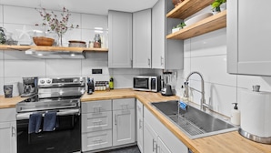 Una cucina moderna con elettrodomestici in acciaio inossidabile, piani in legno e mobili bianchi.