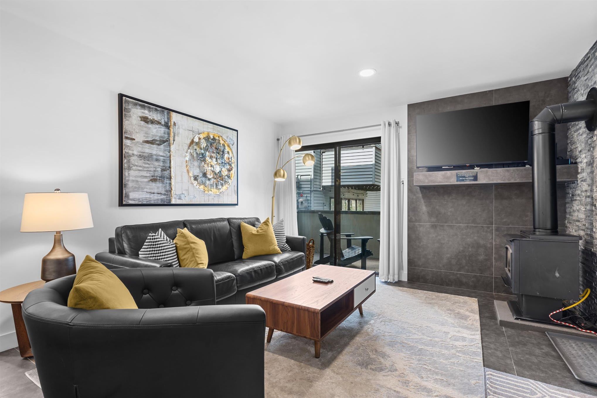 A modern living room with a black leather sofa, a wooden coffee table, and a fireplace.