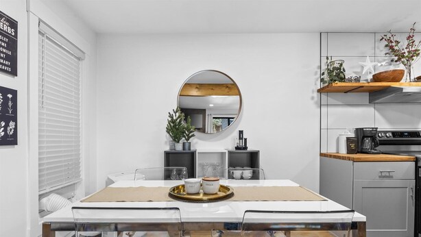 Una cucina moderna con tavolo da pranzo, sedie, uno specchio rotondo e un angolo caffè.