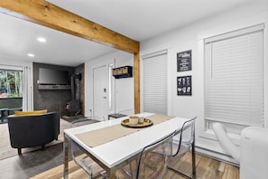 Una cocina moderna con encimera blanca, sofá negro y una mesa de comedor con sillas.