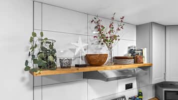 A modern kitchen with a wooden countertop, a white star-shaped decoration, a glass vase with red berries, and a microwave.
