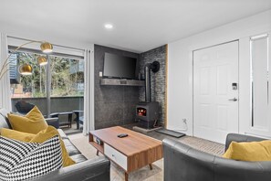 Un salon moderne avec une cheminée, un canapé, une table basse et un téléviseur fixé au mur.