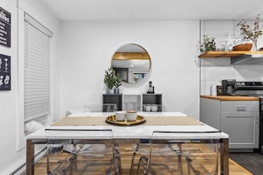 A modern kitchen with a dining table, chairs, a round mirror, and a coffee station. - Relaxed 1BR Mountain Escape | Fireplace & Parking (Steamboat Springs)