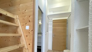 A hallway with wooden flooring, a white textured wall, and a wooden door. - (4.13) Studio cosy skis aux pieds 3 vallées (Les Menuires)