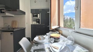 A compact kitchen with a dining area, a microwave, and a coffee maker. - (4.13) Studio cosy skis aux pieds 3 vallées (Les Menuires)