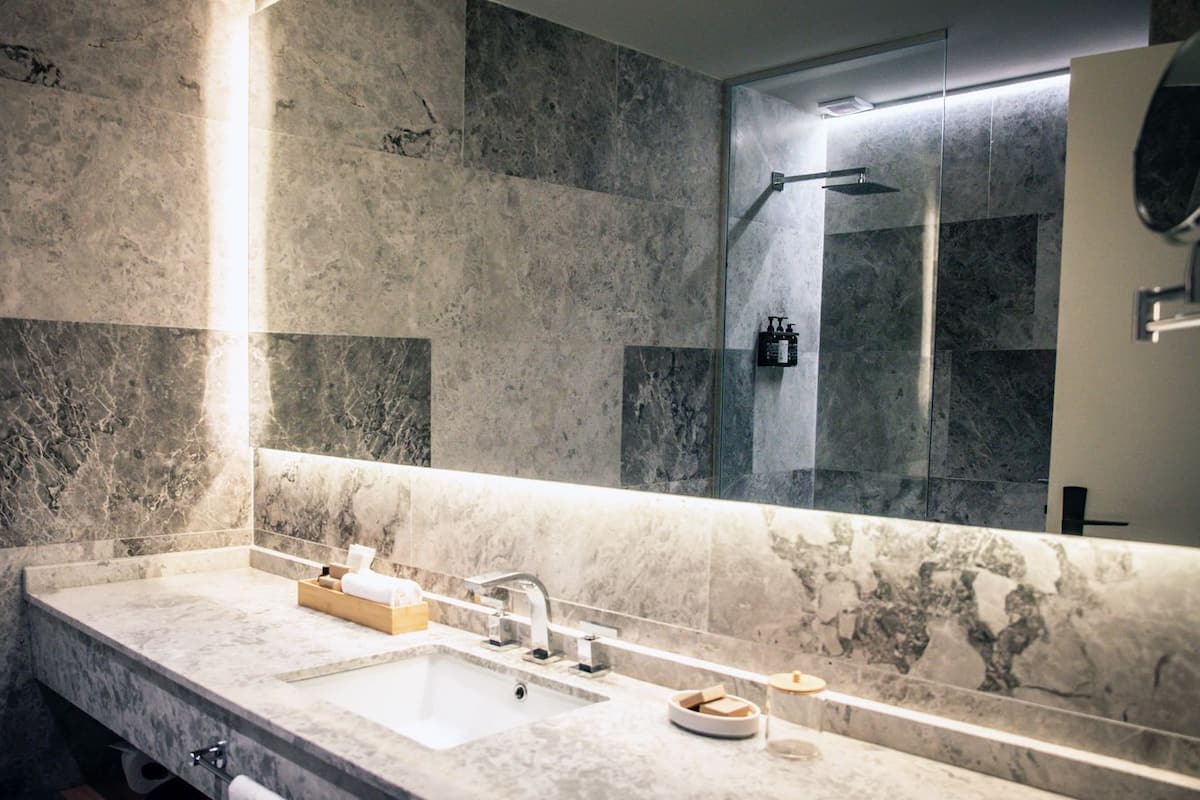 A modern bathroom with a marble sink, a large mirror, and a shower area.