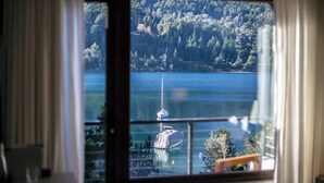 Blick aus einem Fenster auf einen See mit Booten, umgeben von Bäumen.