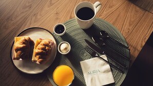 A breakfast tray with croissants, coffee, and a glass of orange juice on a textured mat. - Auria Angostura (Villa La Angostura)