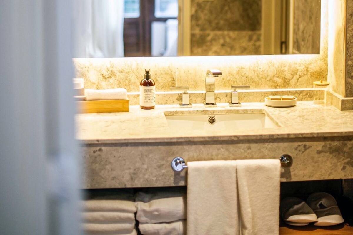 A bathroom with a large mirror, a sink, and a towel rack.