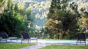 Ein Poolbereich mit Liegestühlen und Blick auf einen bewaldeten Berg.