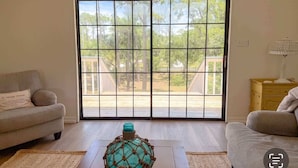 Una habitación con puerta corrediza de vidrio, un sofá, una lámpara y un jarrón decorativo de vidrio.