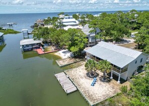 A coastal property with a large house, dock, and surrounding greenery.