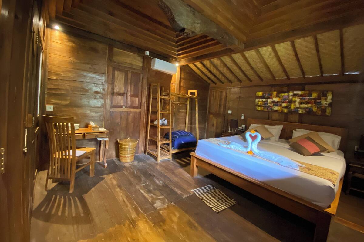 A wooden room with a bed, a desk, and a chair.