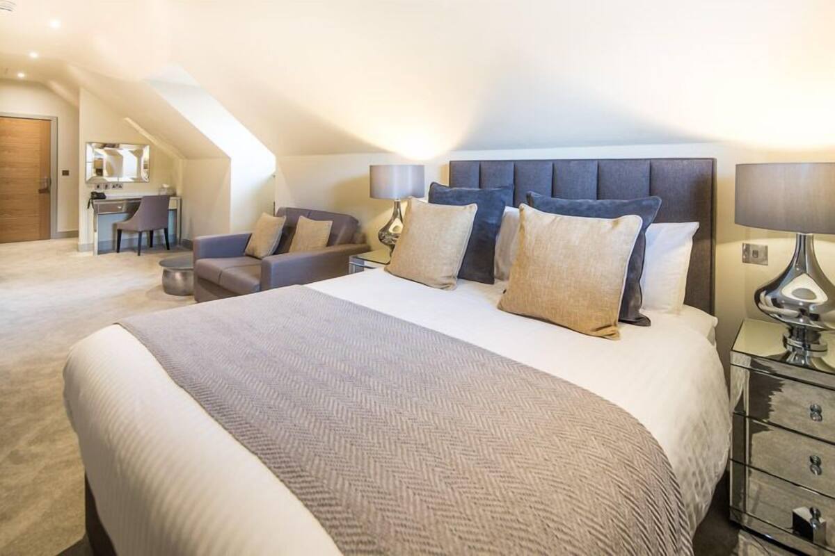 A modern hotel room with a large bed, a desk, and a comfortable seating area.