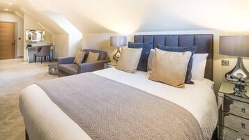 A modern hotel room with a large bed, a desk, and a comfortable seating area.