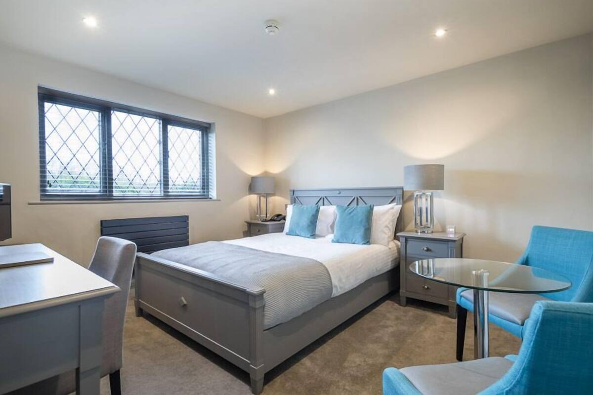 A bedroom with a bed, bedside tables, a desk, and a chair.