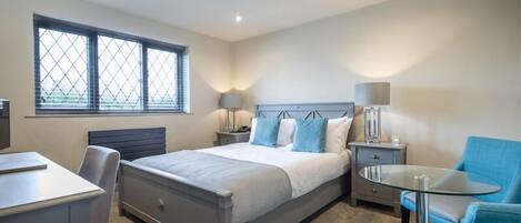 A bedroom with a bed, bedside tables, a desk, and a chair.