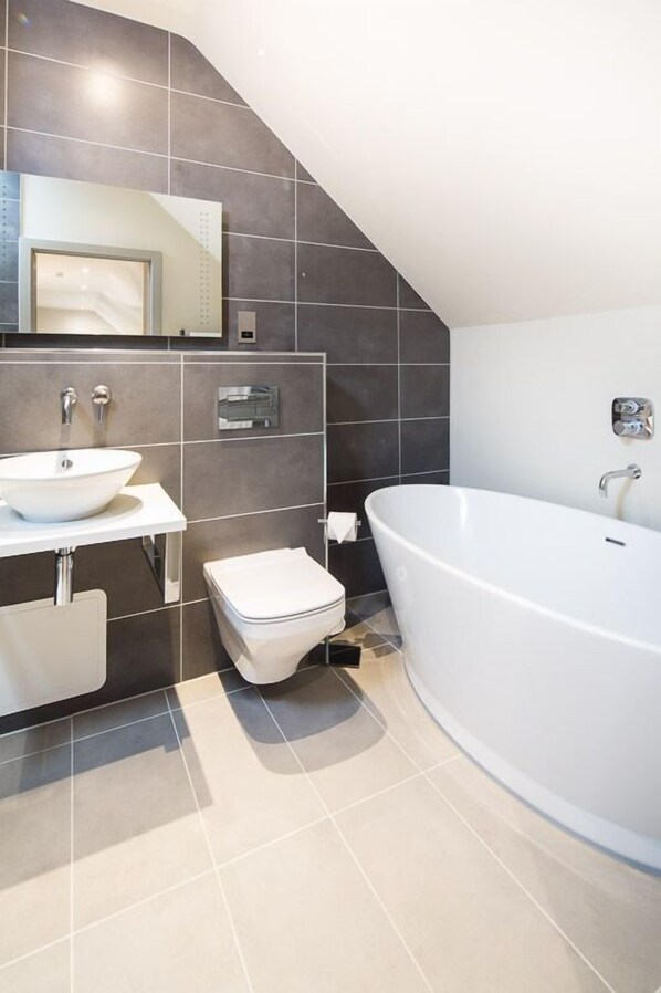A modern bathroom with a freestanding bathtub, a white sink, and a toilet.