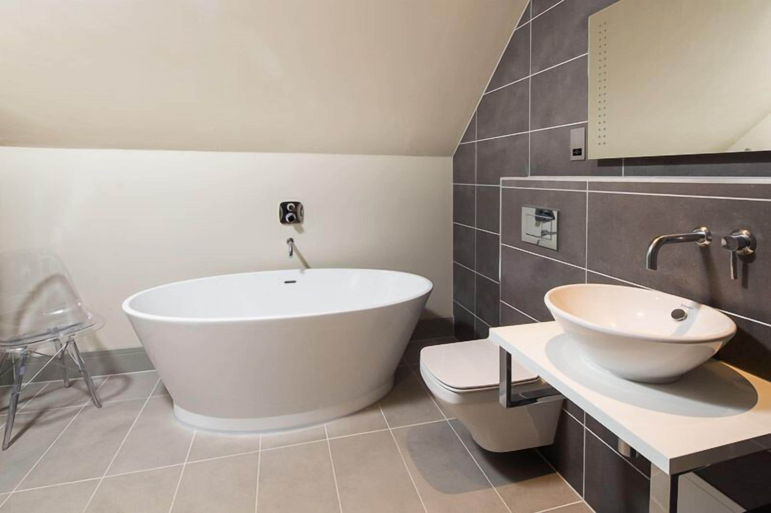 Ein modernes Badezimmer mit einer freistehenden Badewanne, einem Waschbecken und einer Toilette.