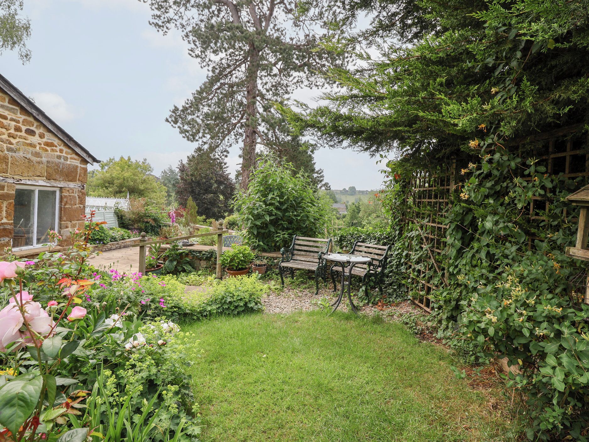 A garden with a stone building, a wooden bench, and a table.
