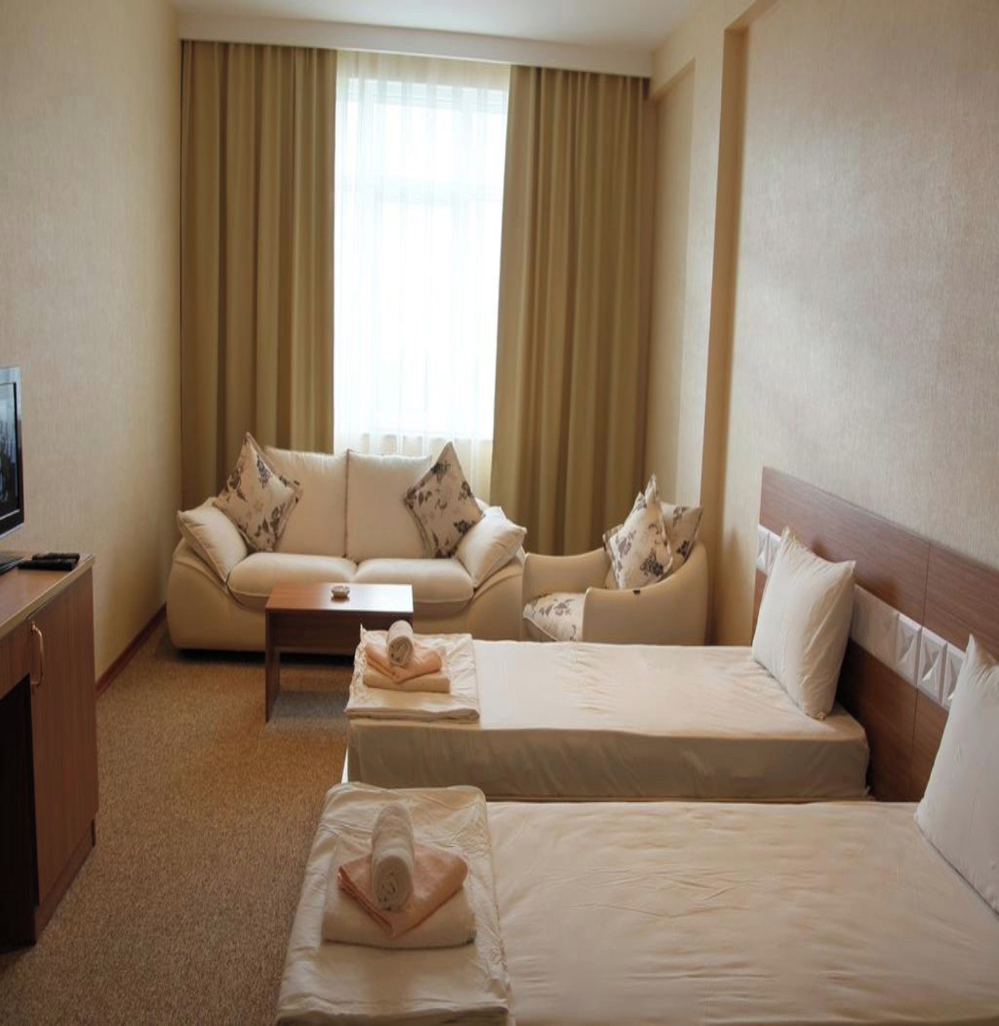 Une chambre d’hôtel avec deux lits, un canapé, une table basse et un téléviseur.