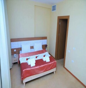 A hotel room with a bed, a nightstand, a door, and a light switch on the wall. - Gabala City Hotel (Gabala)