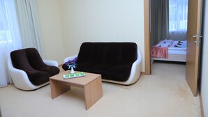 A room with two armchairs, a small table, and a bed with a pink blanket and a rose. - Gabala City Hotel (Gabala)