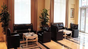 Eine moderne Hotelhalle mit Ledersofas, einem Couchtisch und Topfpflanzen.