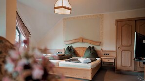 A bedroom with a wooden bed, a nightstand, a dresser, and a hanging light fixture. - In & Out boarding house comfort for four XL rooms (Stolberg)