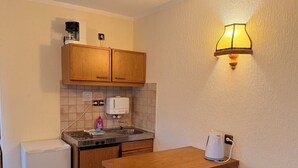A compact kitchen with wooden cabinets, a built-in toaster, a sink, and a coffee maker. - In & Out boarding house comfort for four XL rooms (Stolberg)