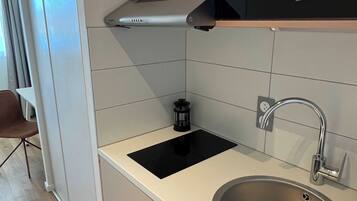 A modern kitchen with a stainless steel sink, a black induction cooktop, and a built-in oven.