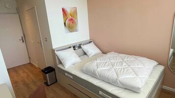 A neatly arranged bedroom with a bed, a small bedside table, and a wall-mounted picture.