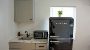 Une cuisine équipée d’un réfrigérateur Galanz noir, d’un four à micro-ondes et d’un évier avec un plan de travail en marbre.
