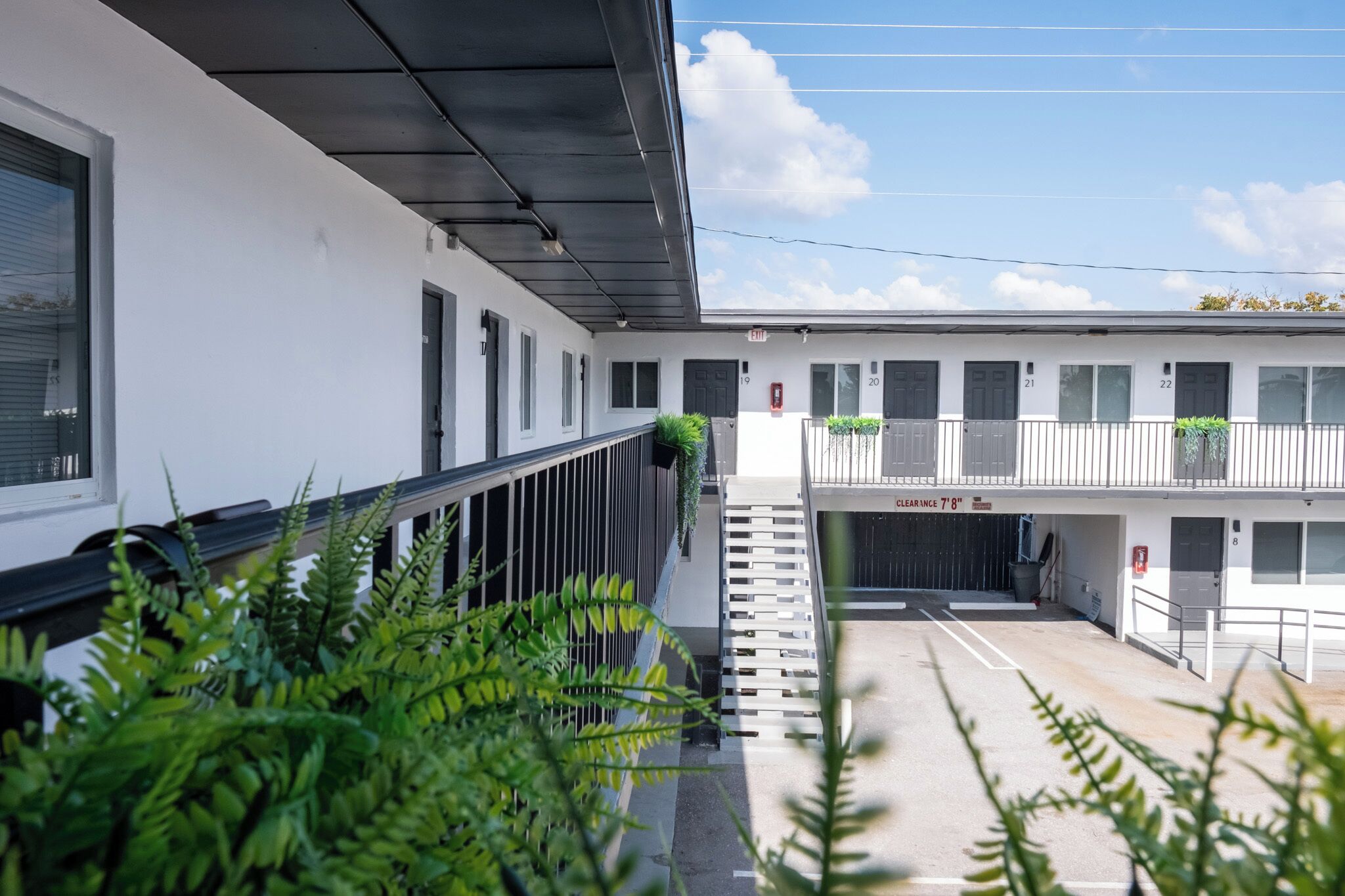 A modern building with numbered doors, a covered walkway, and a clear area in front.