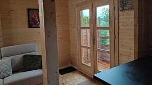 A wooden interior with a sofa, a door with glass panels, and a view of the outside.