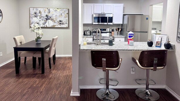 A modern kitchen with white cabinets, stainless steel appliances, and a granite countertop. - I012 - Upgraded 2BD | Pool | DFW South 183/161 (Irving)