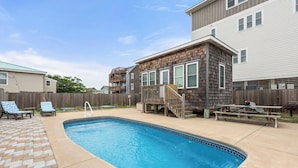 A backyard with a swimming pool, a wooden deck, and a picnic table. - The Barn: Private Pool | Hot Tub (Kill Devil Hills)