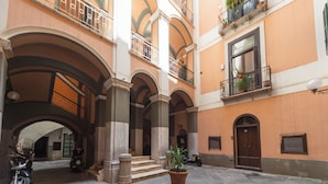 A courtyard with stone flooring, a potted plant, and a motorcycle. - Dimora di Mare (Salerno)