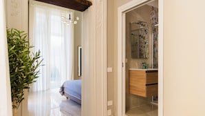 A hotel room with a bed, a bathroom with a shower, and a potted plant. - Dimora di Mare (Salerno)