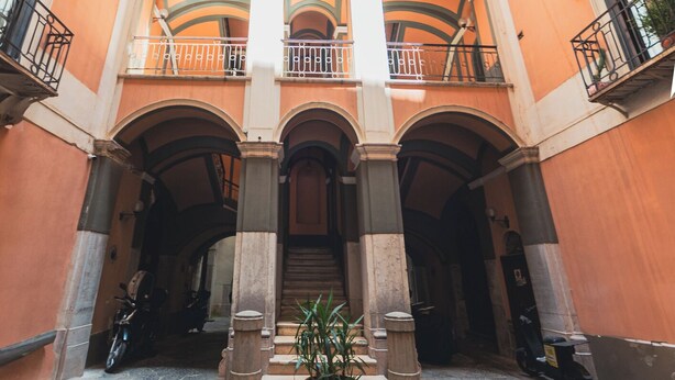 A multi-level courtyard with balconies, potted plants, and a central staircase. - Dimora di Mare (Salerno)