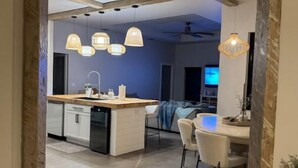 A modern kitchen with a central island, pendant lighting, and a dining area with chairs and a table. - Beaches/Golf - Coastal Retreat w Chefs Kitchen (Port St. Lucie)