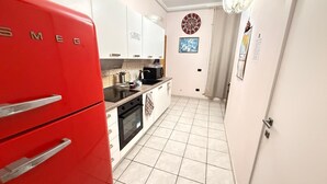 A compact kitchen with white cabinets, a red refrigerator, and a tiled floor. - MAX-FORTUNA (Ragusa)