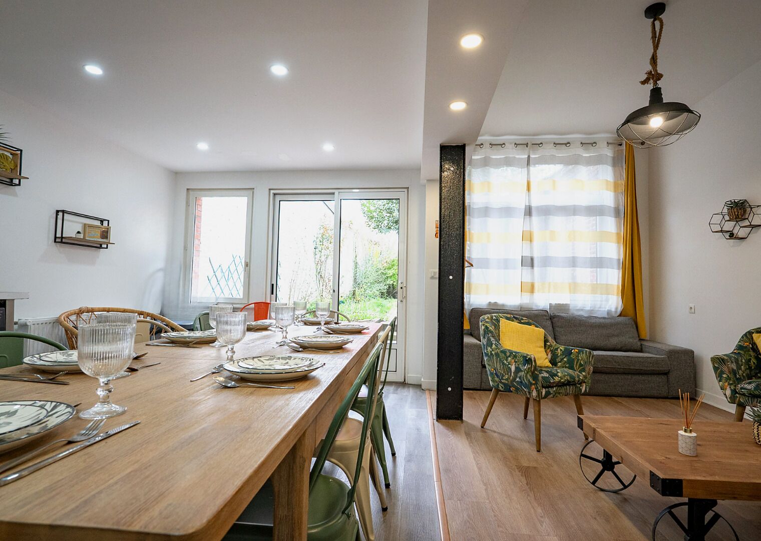 A dining area with a wooden table set for four, chairs, and a view through the window.