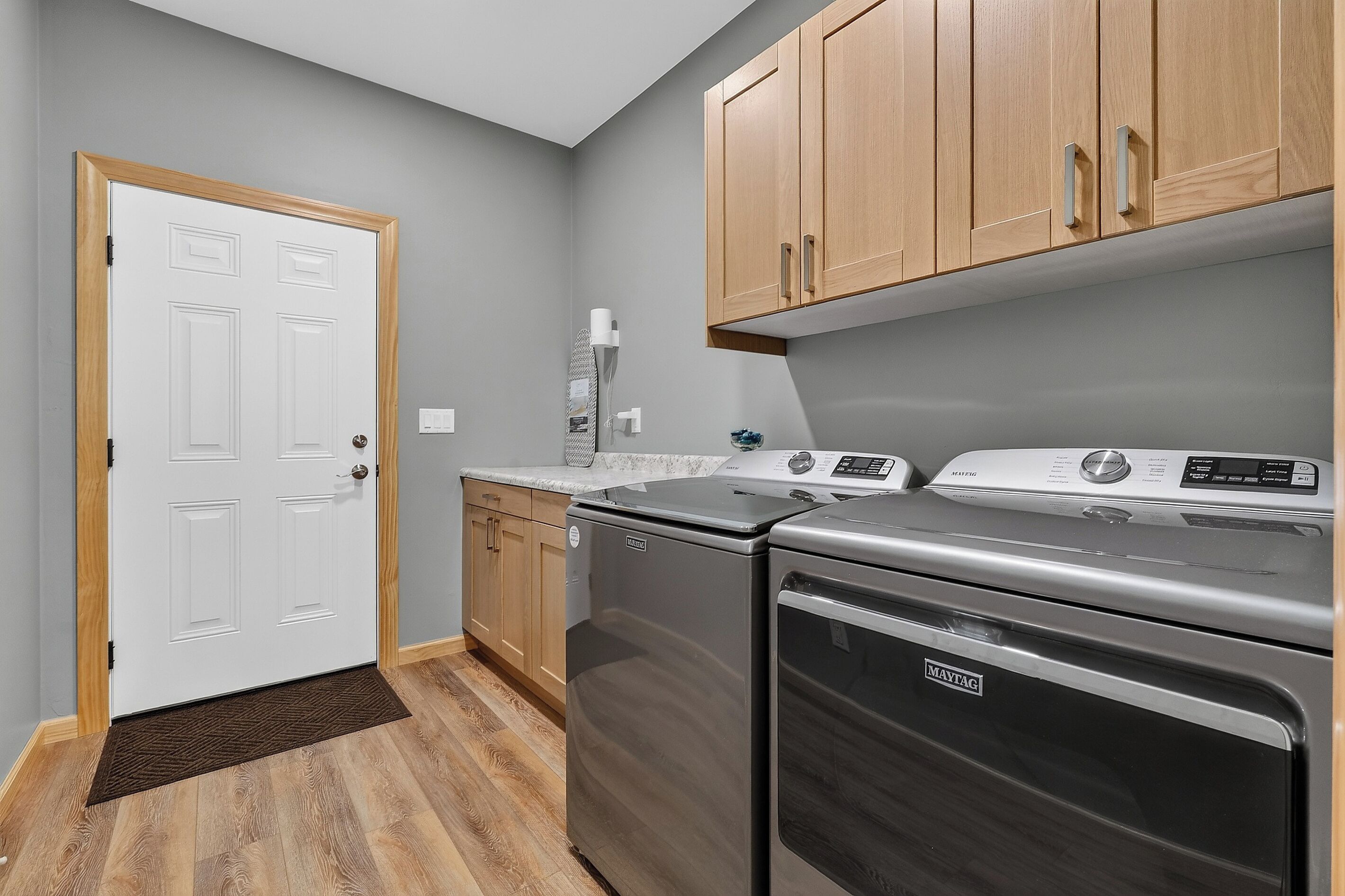 Une cuisine avec une porte blanche, des placards en bois, une cuisinière en acier inoxydable et un lave-linge.