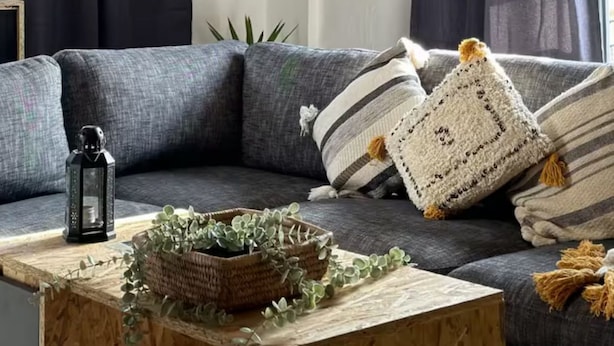 A modern living room with a grey sofa, decorative pillows, a wooden coffee table with a plant, and dark curtains. - Bayt Al Yasmin - Ehden (Ehden)