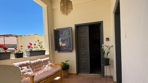 A covered patio area with a cushioned bench, a hanging light fixture, and potted plants. - Bayt Al Yasmin - Ehden (Ehden)