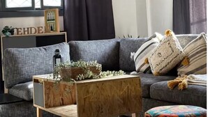 A modern living room with a grey sofa, a wooden coffee table, and a hanging light fixture. - Bayt Al Yasmin - Ehden (Ehden)